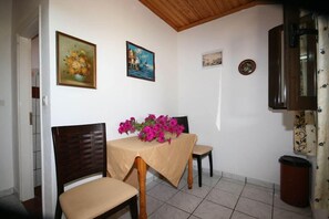 A dining area with a table set for two, a wooden chair, and a cabinet.