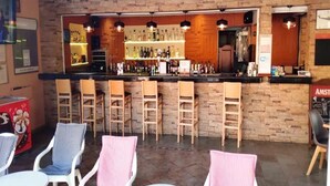 Eine Bar mit Holzsesseln, einer Theke mit verschiedenen Flaschen und einem 'Bud Beer'-Schild.