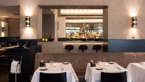 A restaurant interior with a bar area, seating arrangements, and wall-mounted lighting. - Beaumont (Maastricht)