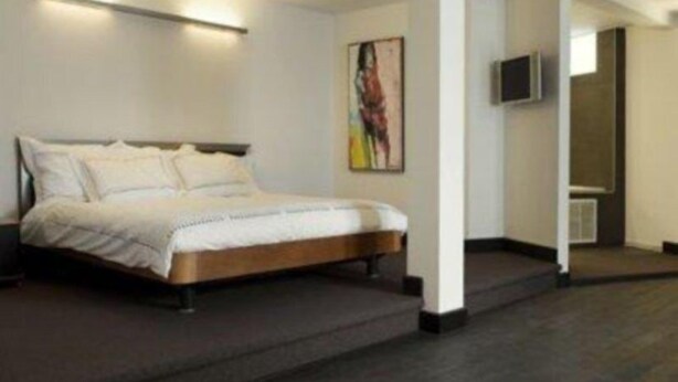 A modern bedroom with a bed, a painting on the wall, and a TV mounted on the wall. - Beaumont (Maastricht)