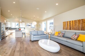 Relax in this open-plan living space with a kitchen and seating area, featuring a sofa, coffee table, and large window with a view.