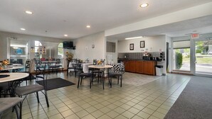 A clean, well-lit restaurant with a kitchen area, multiple tables and chairs, and an exit sign.