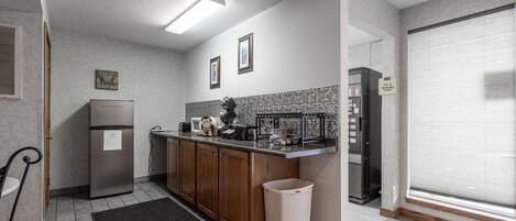 A modern kitchen with a stainless steel refrigerator, wooden cabinets, a countertop with appliances, and a tiled backsplash.