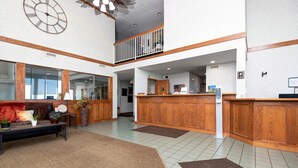 A spacious lobby with a reception desk, a seating area with a sofa and coffee table, and a large clock on the wall.