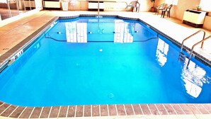 An indoor swimming pool with clear water, a lifebuoy, and a sign indicating the pool's depth.