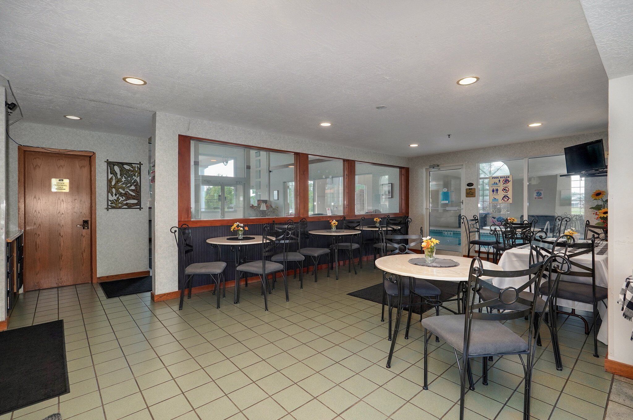 Un restaurant avec plusieurs tables et chaises, une porte en bois et une grande fenêtre.