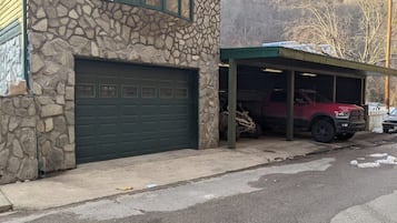 Un bâtiment en pierre doté d’un garage et d’un espace de stationnement couvert.