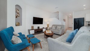 Uma sala de estar moderna com um sofá cinzento, poltronas azuis e uma mesa de centro.