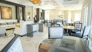 Um lobby de hotel moderno com área de estar central, balcão de recepção e espaço para refeições.
