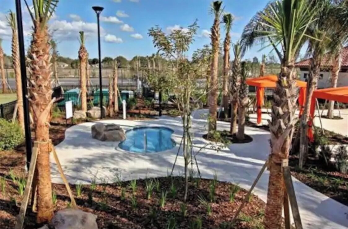 A pool area with palm trees, a gazebo, and a clear sky.