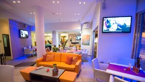 A hotel lobby with a sofa, chairs, a coffee table, and a TV mounted on the wall. - Eligonia Apartments (Ayia Napa)