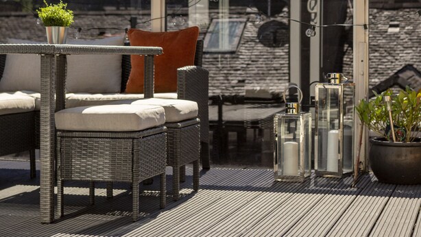 A rooftop terrace with wicker furniture, a potted plant, and a view of a historic building. - The Edinburgh Rooftop Terrace (Edinburgh)