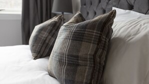 A neatly made bed with plaid pillows and a tufted headboard. - The Edinburgh Rooftop Terrace (Edinburgh)