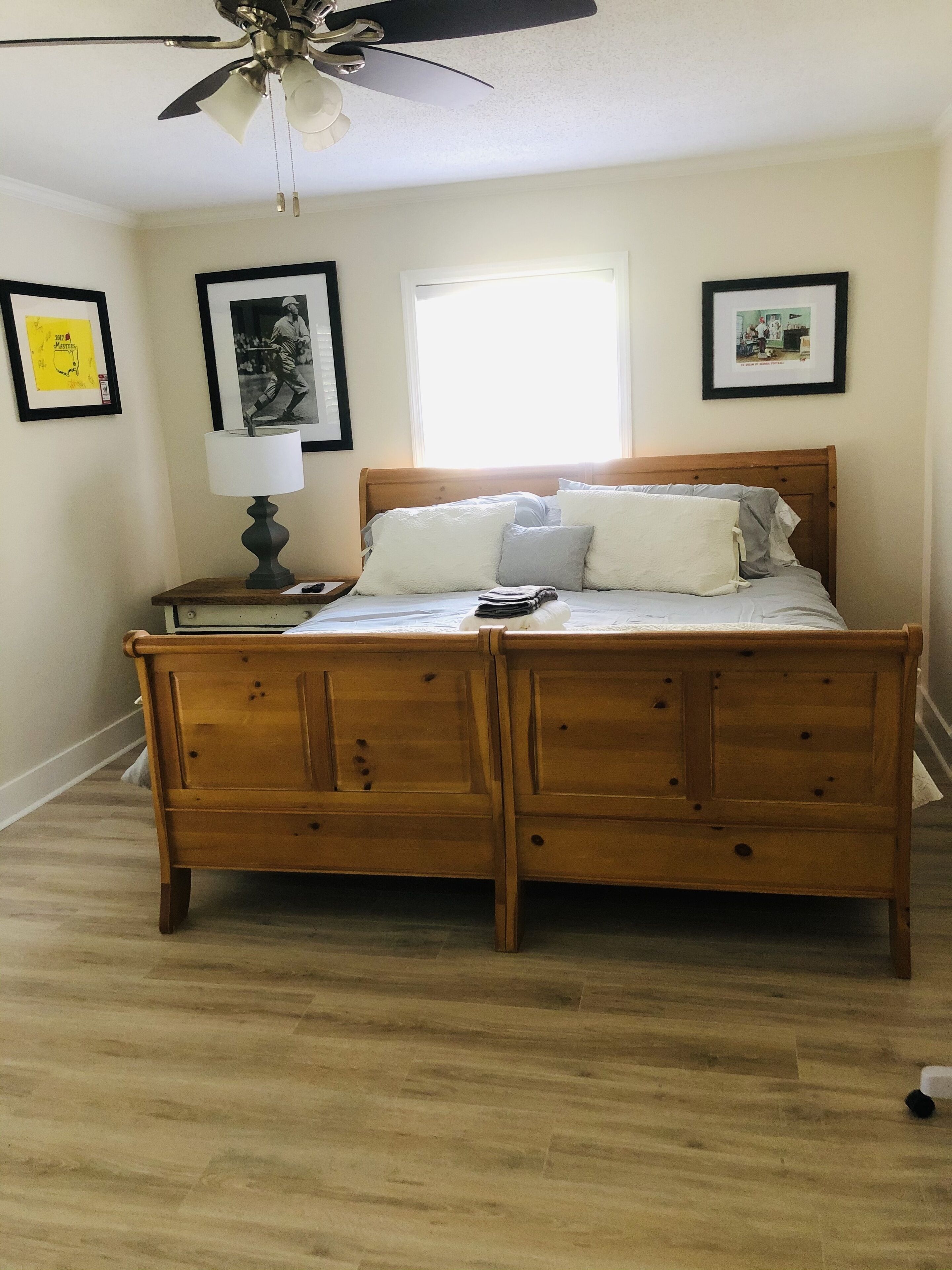 A bedroom with a wooden bed, a nightstand with a lamp, and framed pictures on the wall.
