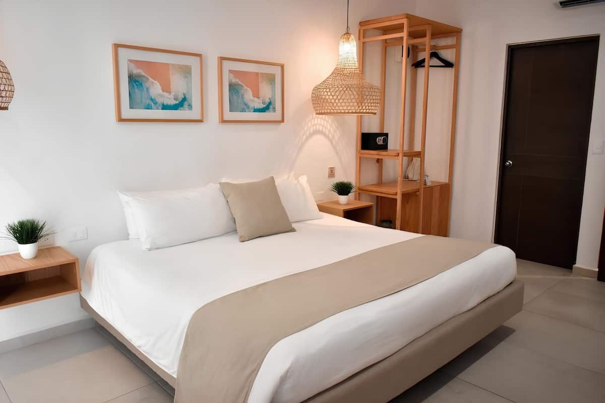 A modern bedroom with a large bed, wooden shelving unit, and two framed artworks on the wall.