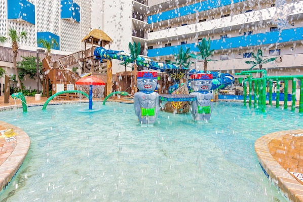 A water park with slides, a pool, and palm trees.