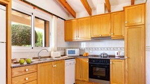 A kitchen with wooden cabinets, a microwave, a stove, and a dishwasher. - Villas Menorca Sur (Alayor)