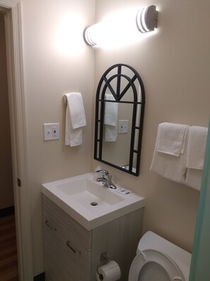 A bathroom with a white sink, a mirror, and two towels hanging on the wall. - Red Crown Inn (Laurel)