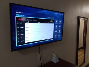 A digital channel guide on a wall-mounted screen displaying various TV channels and their on-screen times. - Red Crown Inn (Laurel)