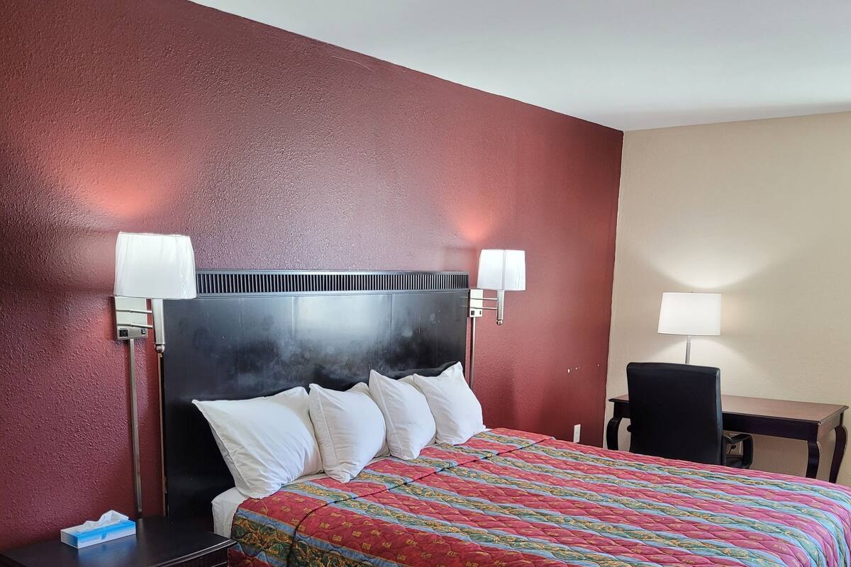 A hotel room with a bed, bedside tables, a desk, and a chair.