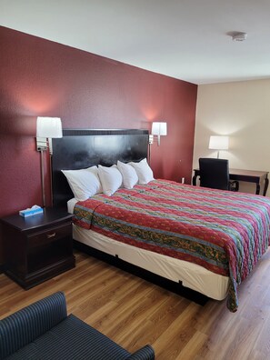 A hotel room with a bed, bedside tables, a desk, and a chair. - Red Crown Inn (Laurel)