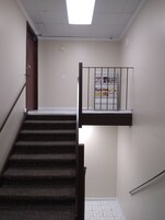 Una escalera con barandilla y un rellano con pasamanos.