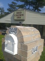 Un buzón con el número 3440, un letrero del Red Crown Inn y el logotipo de US Mail.