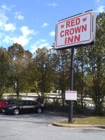 Placa do Red Crown Inn, com um carro de segurança estacionado perto.