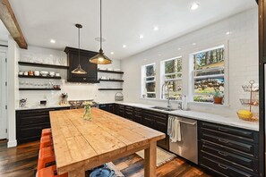 Une cuisine moderne avec une table en bois, des meubles noirs et une grande fenêtre.