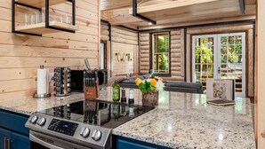 A modern kitchen with wooden walls, a granite countertop, and a built-in stove. - New Luxury Cabin w/ King Beds, Game Room and Fire Pit  (Eureka Springs)