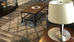 A living room with a TV, a coffee table, a lamp, and a ceiling fan.
