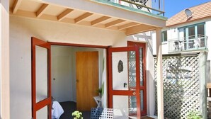 A small, enclosed outdoor area with a wooden door, a small table, and a chair. - Central Akaroa Retreat - Balcony & Parking -Tumeke Akaroa (Akaroa)