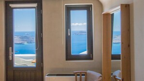 A room with a view of the sea, a door, a window, and a chair. - Chic Hotel Santorini (Santorini)