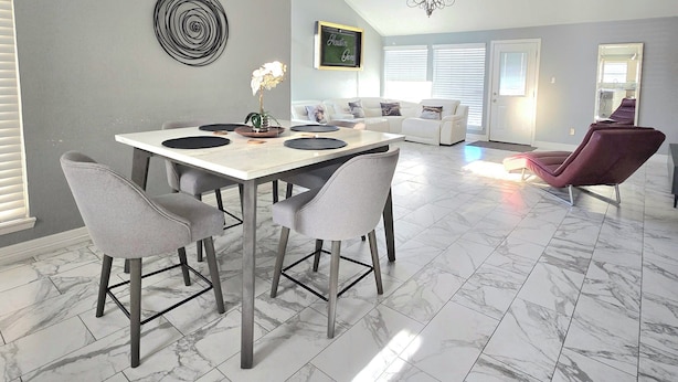 Un comedor amplio con un ventilador de techo alto, una mesa de comedor con sillas y una lámpara moderna.