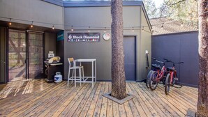 Ein moderner Außenbereich mit Terrasse, einem Grill, einem Tisch, Stühlen und Fahrrädern, die an einer Wand lehnen.