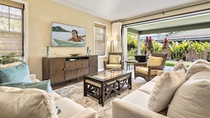 A living room with a sofa, armchairs, a coffee table, a cabinet, a painting, and a view of the outdoors.