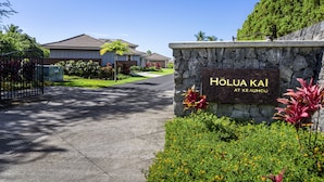 A residential area with a stone wall sign reading "HOLUA KAI AT KE AUHOU".
