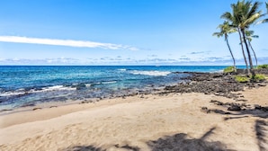 Una playa con aguas azul cristalino, orilla arenosa y algunas palmeras.