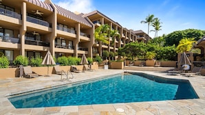 Un hotel con piscina, varios balcones y zonas de estar al aire libre.