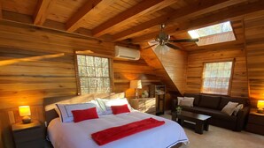 Ein gemütliches Schlafzimmer in einer Holzhütte mit einem großen Bett, einer Couch und einem Deckenventilator.