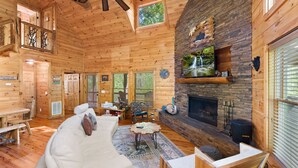 A log cabin interior with a fireplace, wooden furniture, and a view of the outdoors. - Luxury 3BD 3BA Cabin. Hot Tub,Pool Table,BBQ.Close to Helen, GA.Great for Groups (Cleveland)