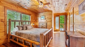 A wooden cabin bedroom with a bed, a ceiling fan, and a wooden bench. - Luxury 3BD 3BA Cabin. Hot Tub,Pool Table,BBQ.Close to Helen, GA.Great for Groups (Cleveland)