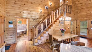 A wooden cabin interior with a staircase, a dining area, and a 'Bear Crossing' sign. - Luxury 3BD 3BA Cabin. Hot Tub,Pool Table,BBQ.Close to Helen, GA.Great for Groups (Cleveland)