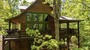 A wooden cabin with a balcony and a covered deck, surrounded by trees. - Luxury 3BD 3BA Cabin. Hot Tub,Pool Table,BBQ.Close to Helen, GA.Great for Groups (Cleveland)