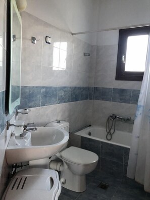 Uma casa de banho compacta com lavatório, sanita e banheira.
