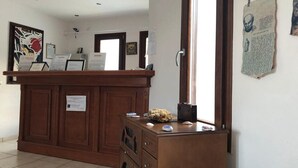 Un comptoir d’accueil avec un revêtement en bois, une œuvre d’art encadrée au mur et un panneau d’affichage où sont accrochés des documents.