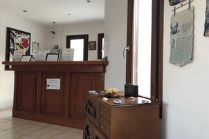Una recepción con detalles de madera, una obra de arte enmarcada en la pared y un tablón de anuncios con documentos.