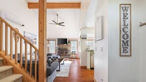 Amplia sala de estar con una escalera de madera, una chimenea y un cartel que dice 'WELCOME'.