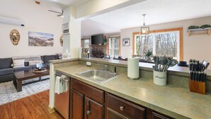 Una cocina moderna con una isla grande, electrodomésticos integrados y una zona de comedor con sofá y mesa de centro.