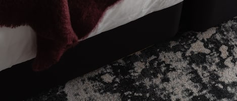 A bed with a white mattress and a dark-colored blanket.